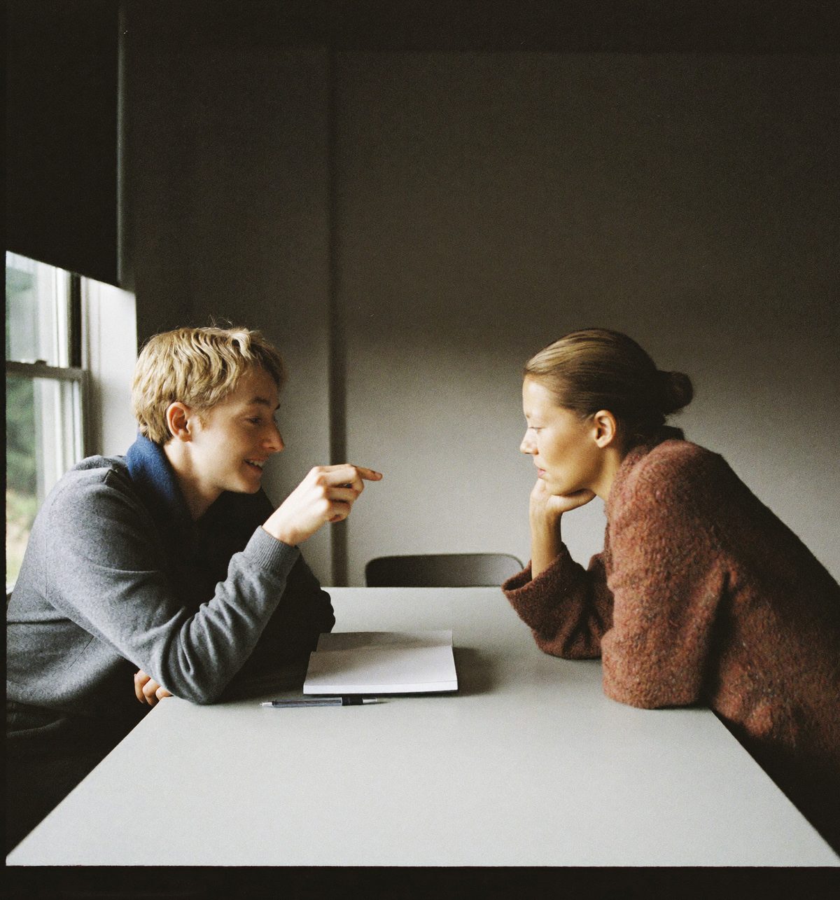 Two colleagues in conversation across the corner of a table.